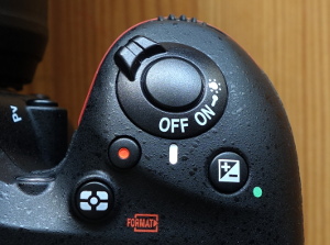 Metering mode, exposure compensation, and red-dot button below the concentric trigger and power switch.